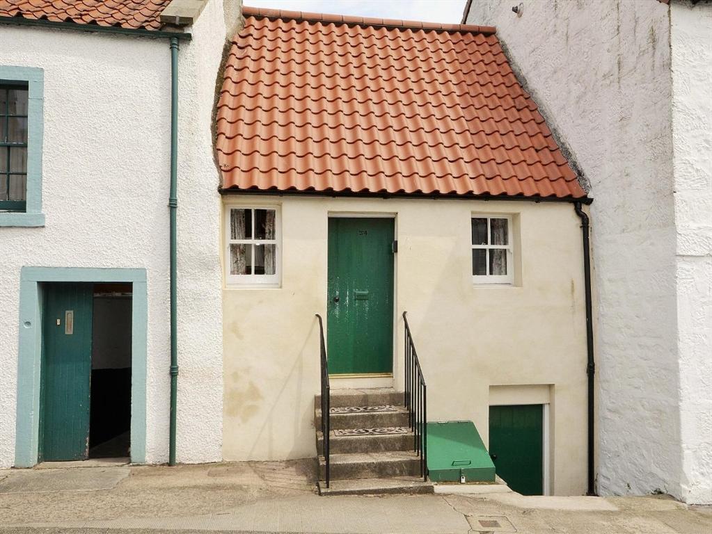a white house with a green door and stairs at The Wee Hoose in Kinghorn