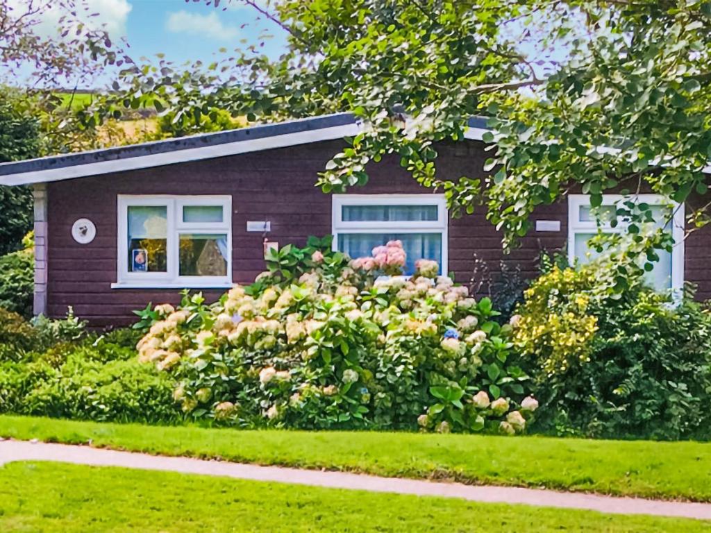a house with a flower garden in front of it at Hollyhocks Bungalow - Uk39617 in Welcombe