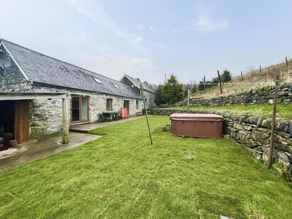a stone house with a large yard next to a stone wall at Cefn Y Meirch in Bala