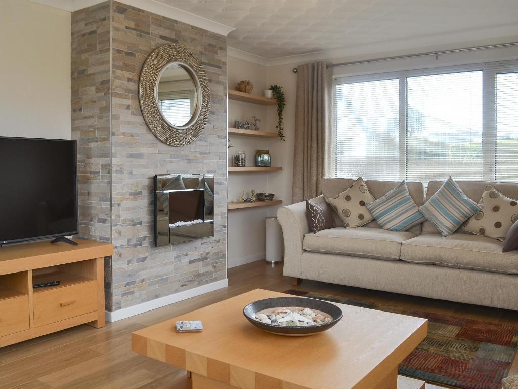 a living room with a couch and a tv at Stepping Stones in Trearddur