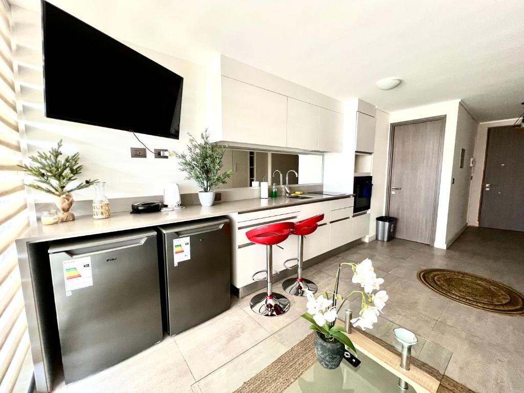 a kitchen with a refrigerator and a tv on the wall at Apartamento Reñaca Live in Viña del Mar