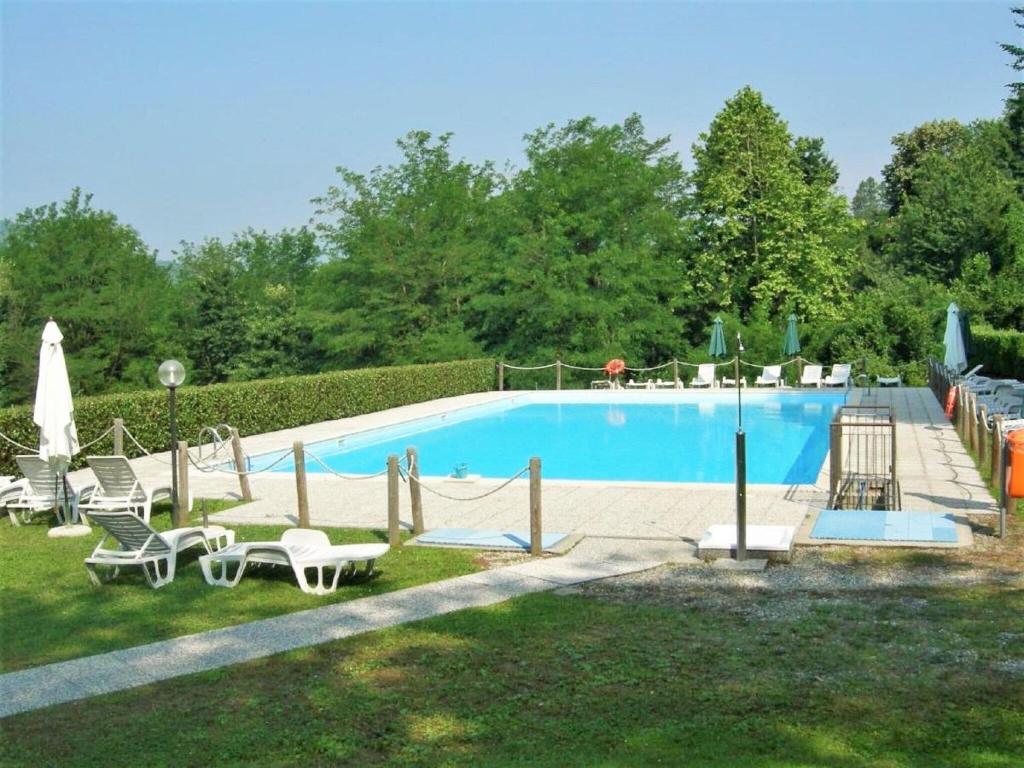 a swimming pool with chaises and chairs in a yard at Belvilla by OYO BOS03 3 in Grantola