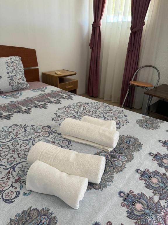 twee witte handdoeken bovenop een bed bij Apartments Airport Golubovci 2 in Podgorica