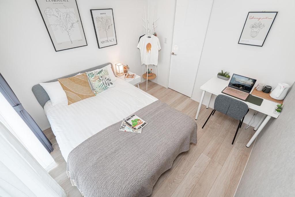 een slaapkamer met een bed en een bureau met een laptop bij ZAITO Tokyo Skytree Yokokawa III 錦糸町駅から徒歩９分 in Tokyo