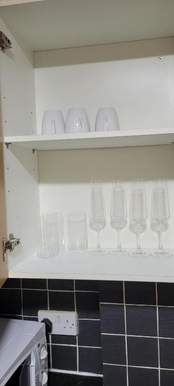 a row of wine glasses on a shelf in a kitchen at 13 Decent Homes in Dukinfield