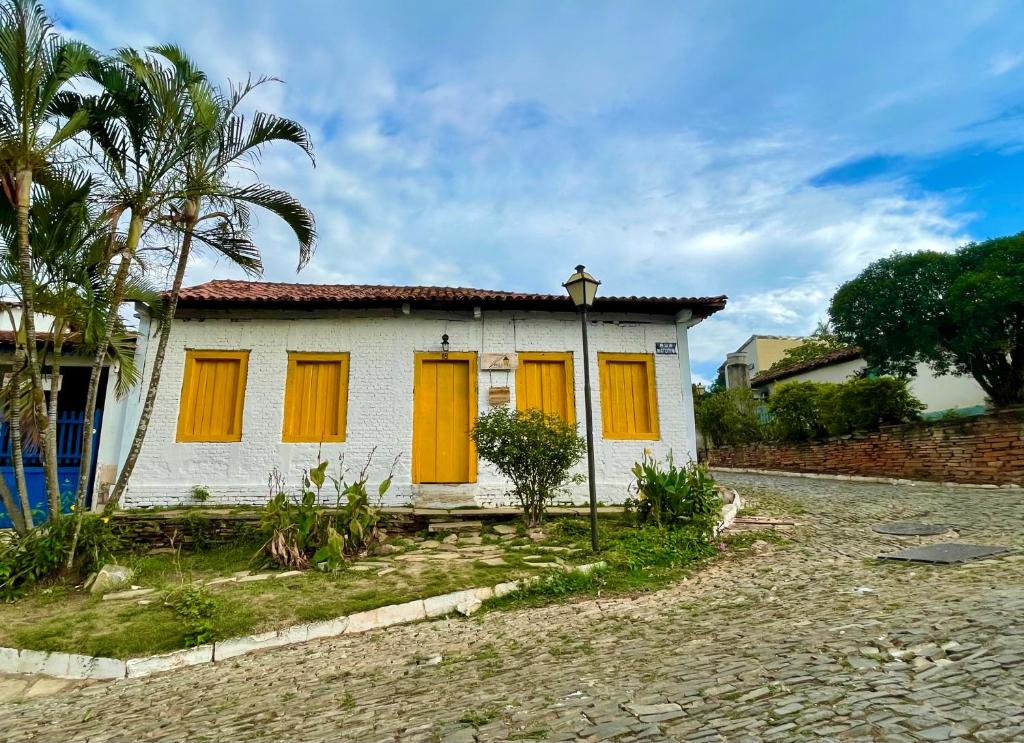una pequeña casa con puertas naranjas en una calle en HOSTEL DA LÚ en Pirenópolis