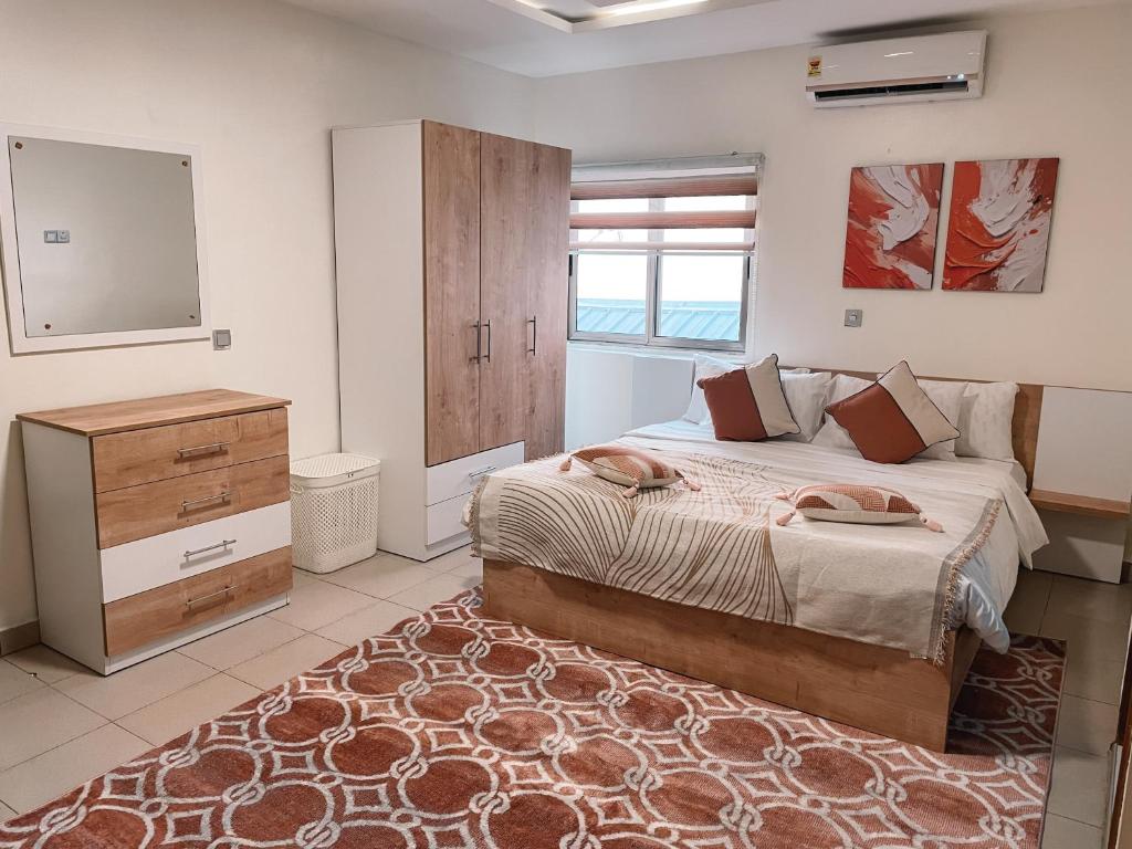 a bedroom with a bed and a dresser and a mirror at Sky Suites East Legon in Accra