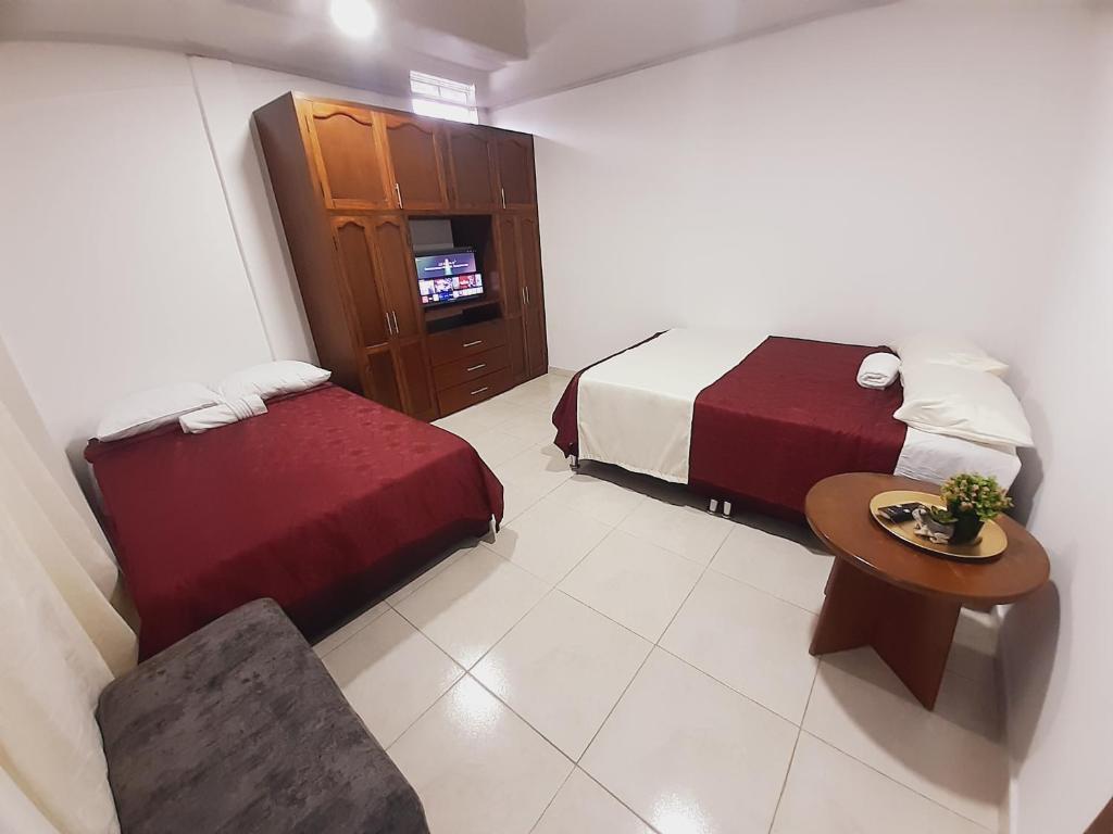 a hotel room with two beds and a table and chair at Apartamento en centro de Popayán in Popayan