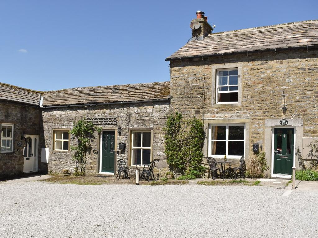 ein altes Steinhaus mit grünen Türen und Fenstern in der Unterkunft Poppy Cottage in Buckden