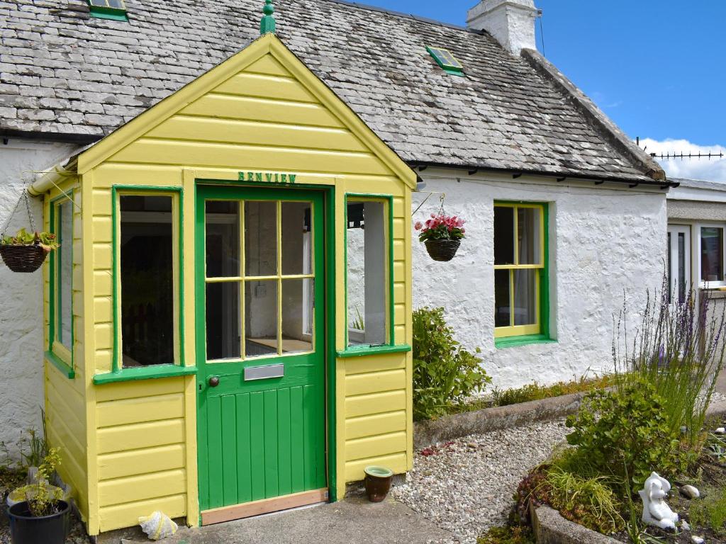 a yellow and green shed in front of a house at Ben View in Orbliston