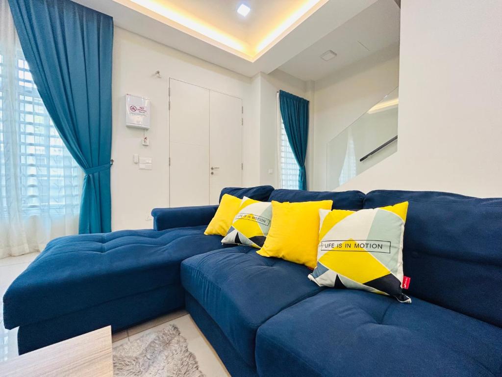 a blue couch with yellow pillows in a living room at Insyirah Homestay Melaka in Melaka