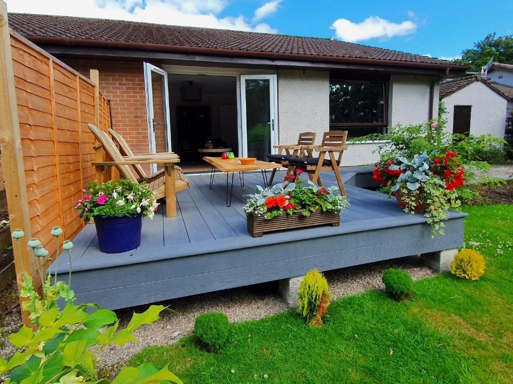 a deck with two potted plants and a table at Ferry Cottage in Pitlochry
