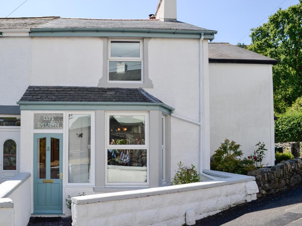 una casa blanca con una puerta azul en Llys Deulyn en Trefriw