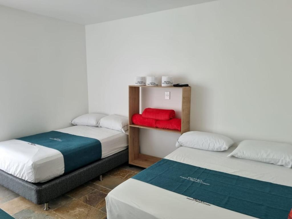 Habitación con 2 camas y almohada roja. en Hotel Puerto Triunfo, en Doradal