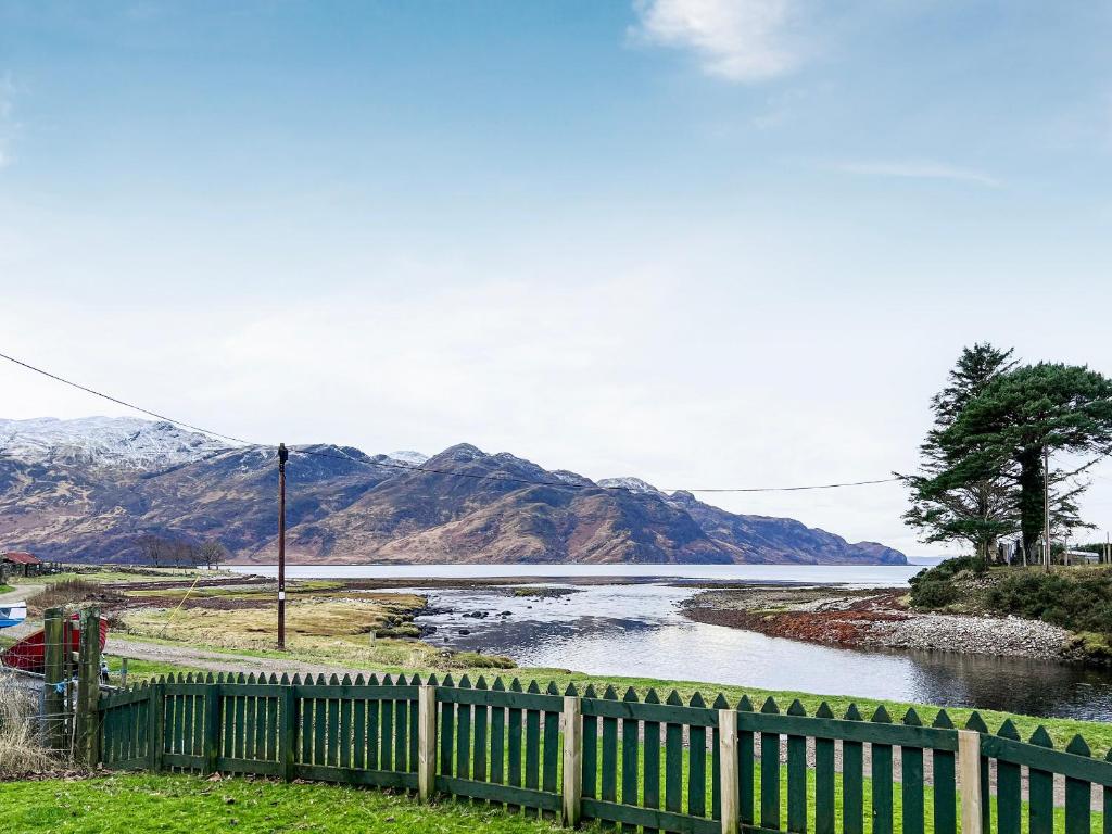 a river with a fence and mountains in the background at The Old Post Office in Arnisdale