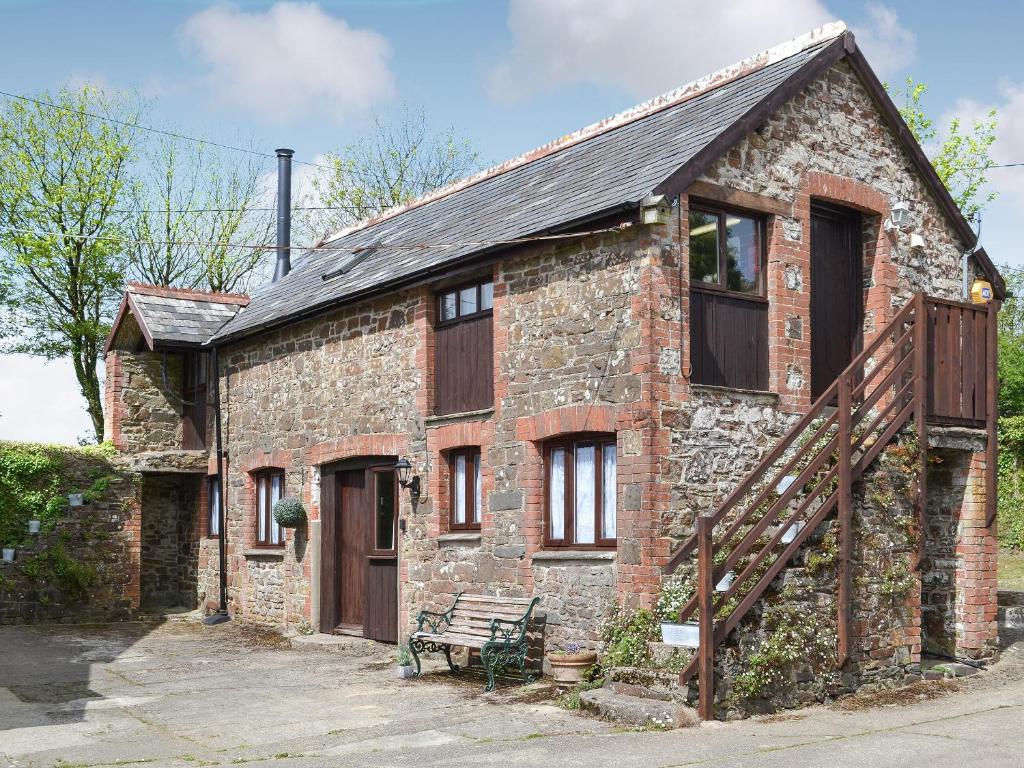 an old brick house with a bench in front of it at The Old Coach House in Woolfardisworthy