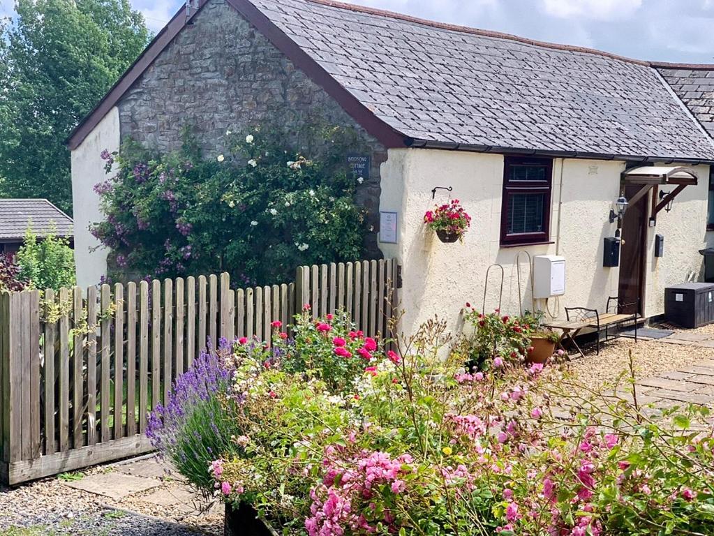 a small white house with a fence and flowers at Birdsong Cottage in Hartland