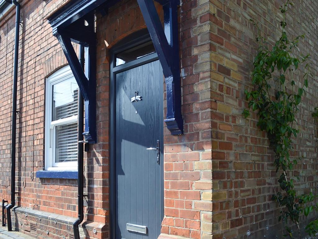 una puerta azul en el lateral de un edificio de ladrillo en Dragonfly Cottage en Beverley
