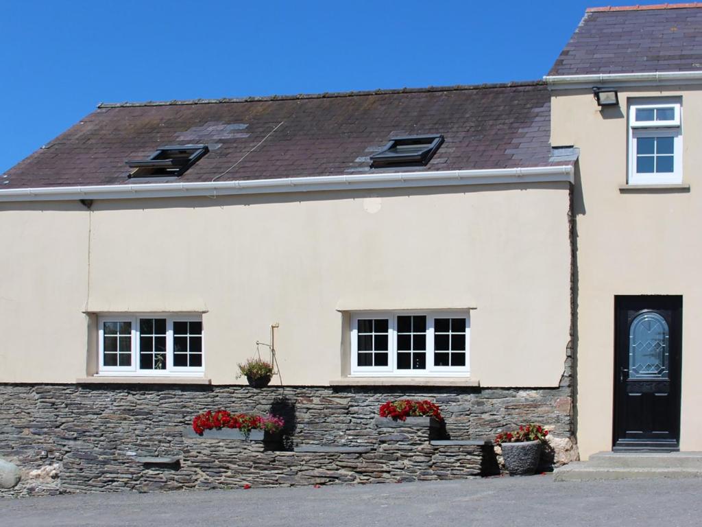 a white house with two windows and a stone wall at The Carthouse - Uk13184 in Cwm-Morgan