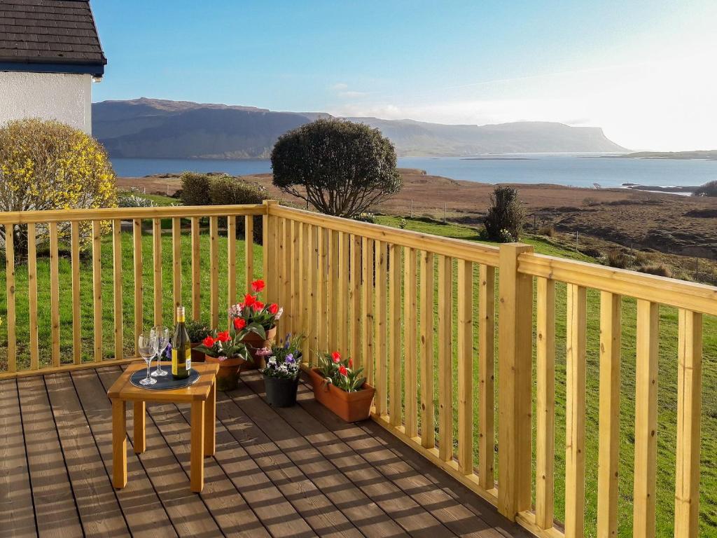 a wooden fence on a deck with a table and flowers at Island Views in Lagganulva
