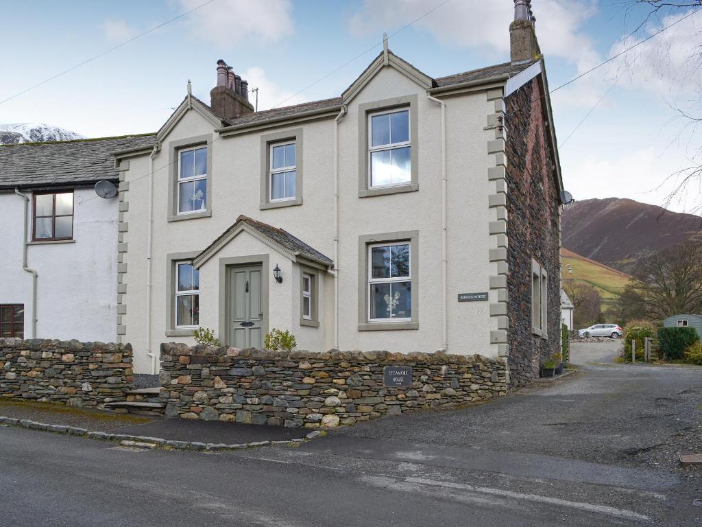 a white house with a stone wall at Rowan House in Threlkeld