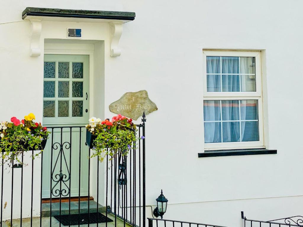 a white house with two flowers on a gate at Mill Head Cottage in Ilfracombe