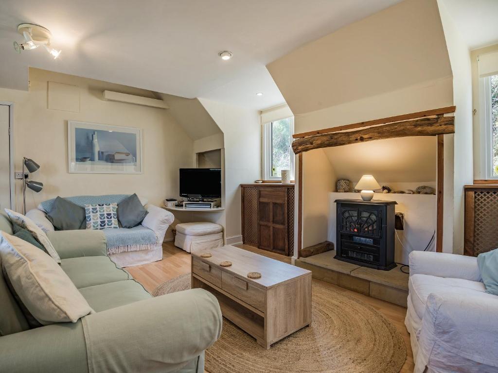 a living room with two couches and a fireplace at Clock Cottage in Branscombe