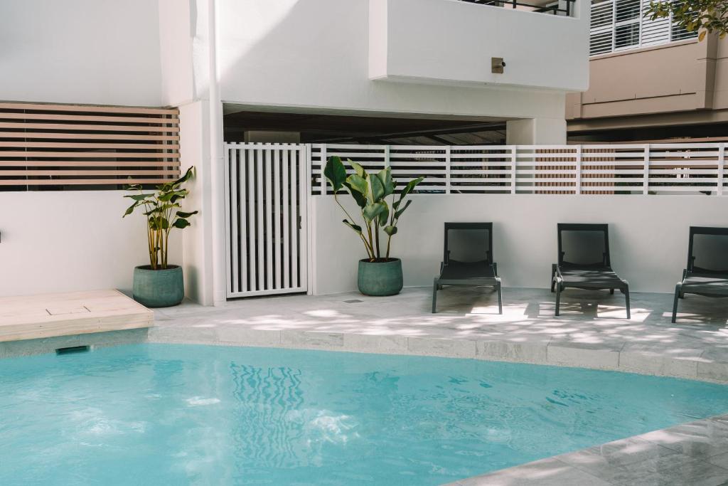 una piscina con due sedie e un edificio di Bella Casa Noosa a Noosa Heads