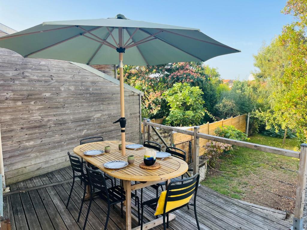 une table en bois avec un parasol sur une terrasse dans l'établissement La Yonnaise, à La Roche-sur-Yon