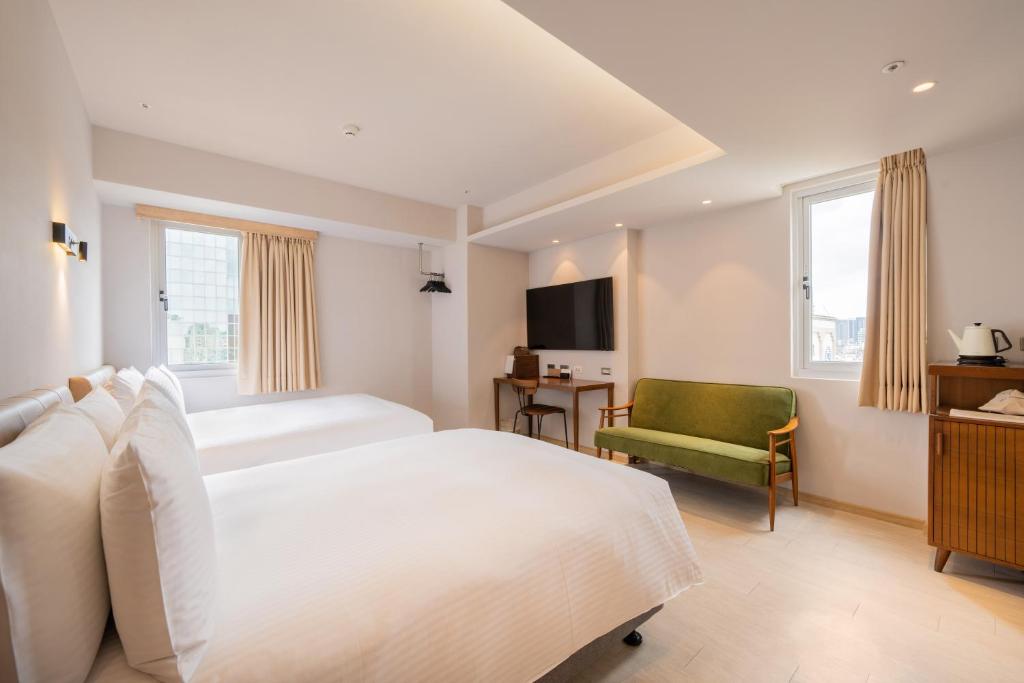 a bedroom with a white bed and a green chair at Inns Hotel in Kaohsiung