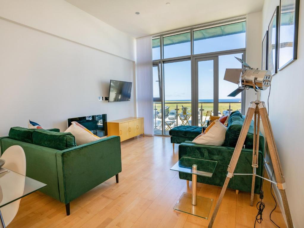 a living room with two green couches and a camera at Penthouse 47 Zinc in Newquay