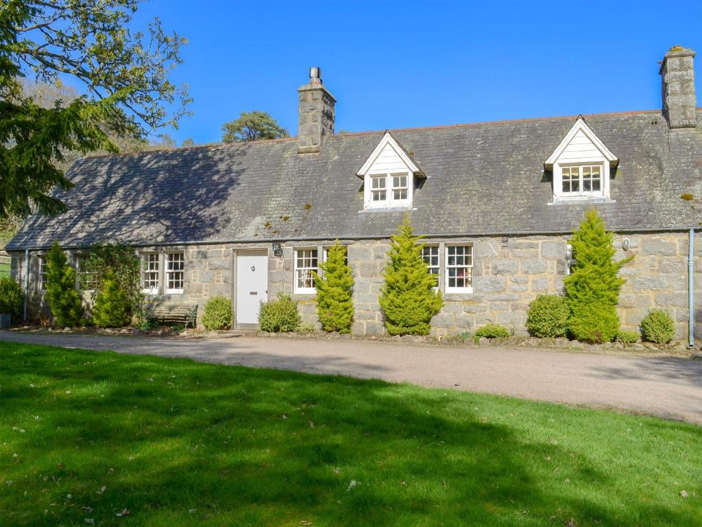 a stone house with trees in front of it at Tressady Coach House in West Langwell