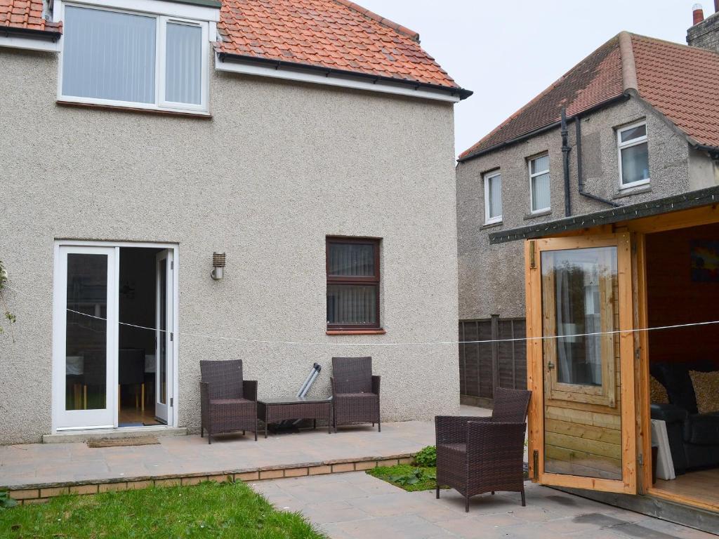 a house with a patio with chairs in it at Lynbank in Seahouses