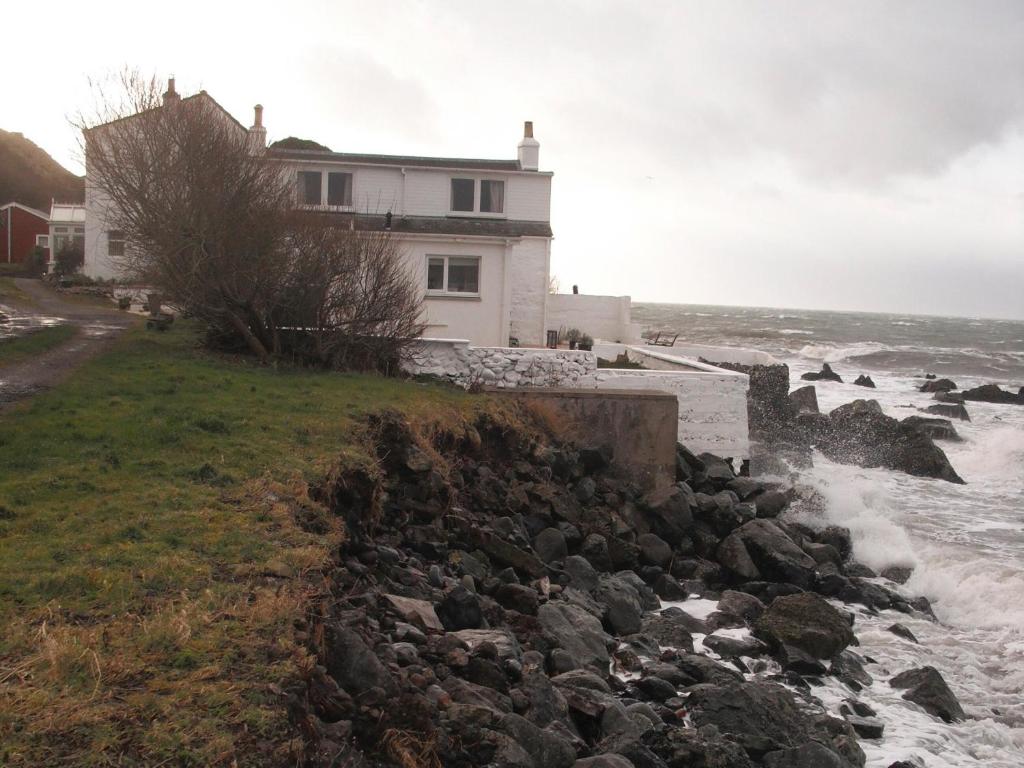 a house on a cliff next to the ocean at Gull Cottage in Lendalfoot