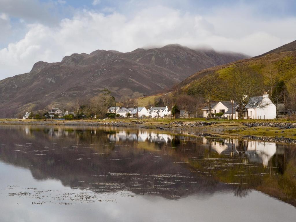 a body of water with houses and mountains in the background at Lag Cottage in Dornie
