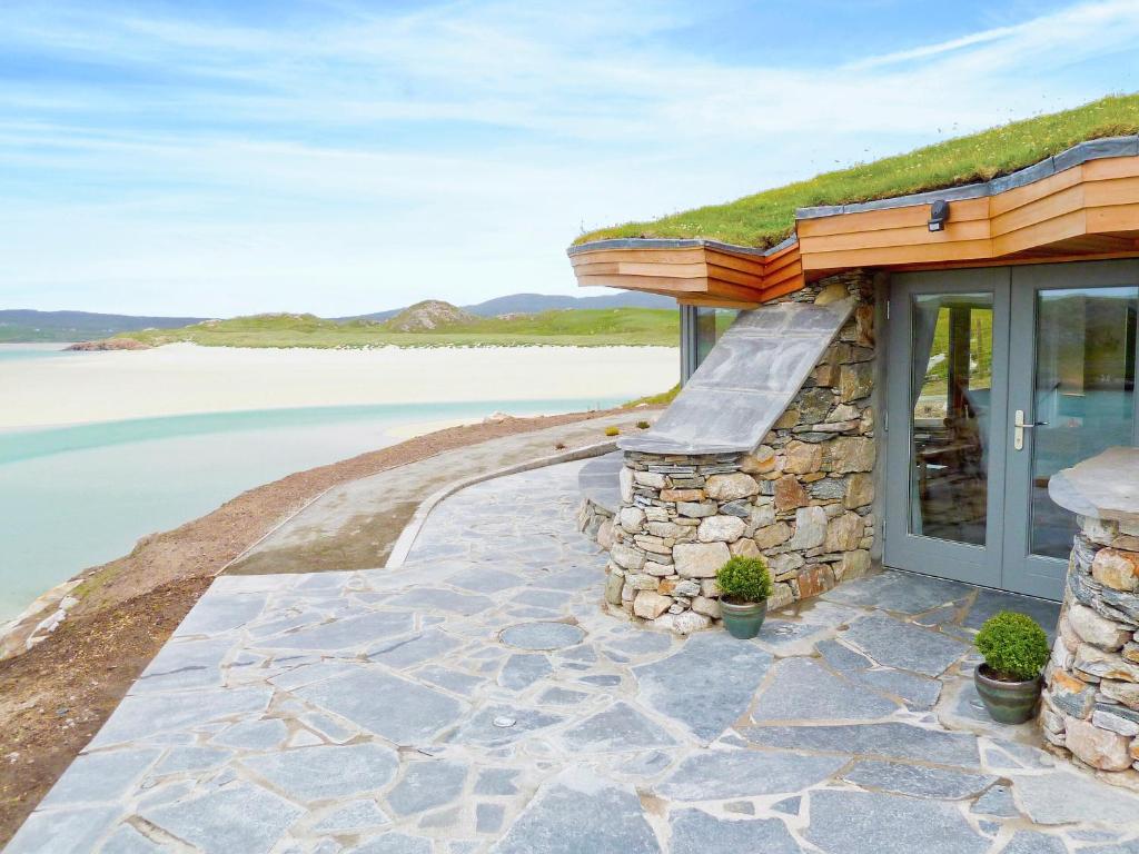 a house with a stone walkway next to the water at Beach Bay Cottage in Mangersta