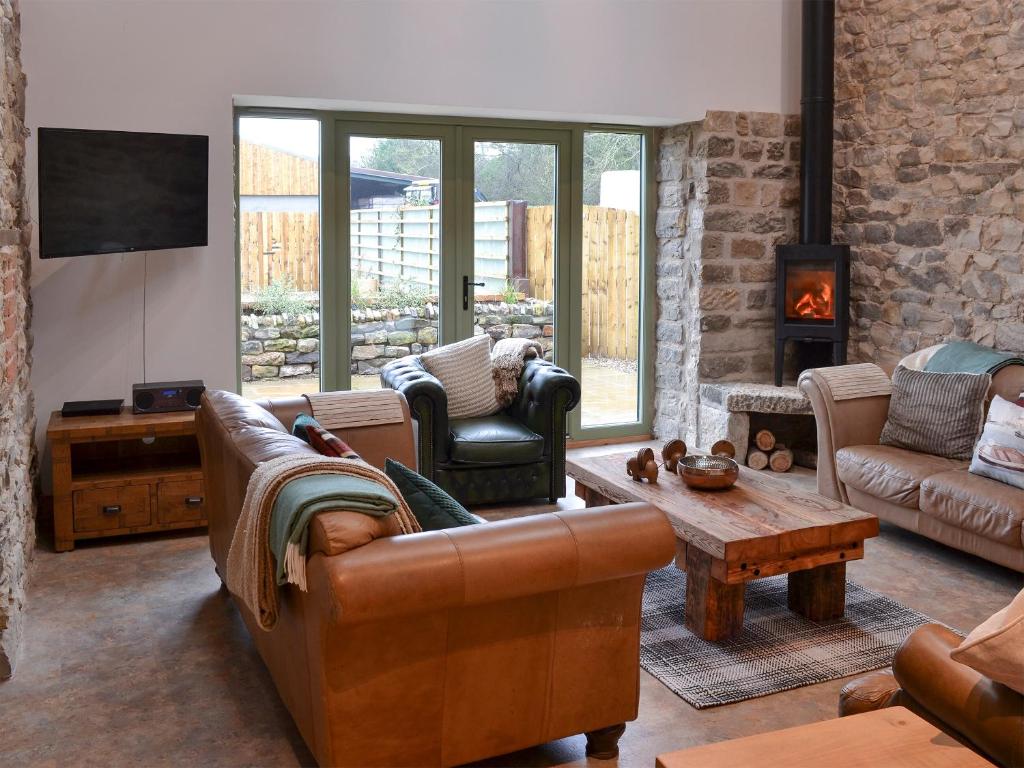 a living room with leather furniture and a fireplace at The Barn in Staintondale