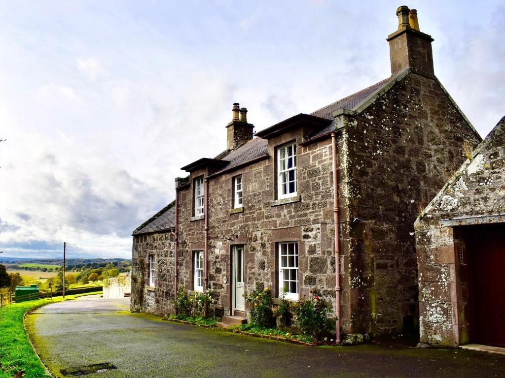 an old stone house on a road at Straton Cottage in Saint Cyrus