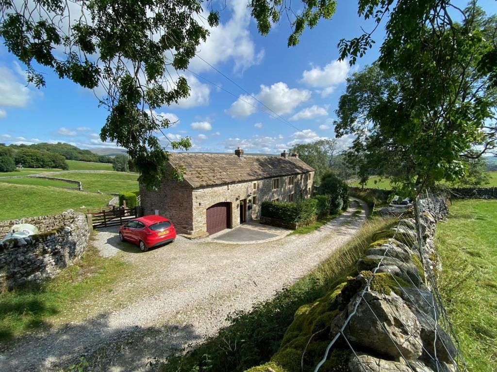 an old stone house with a red car parked in front at Lane House in Threshfield