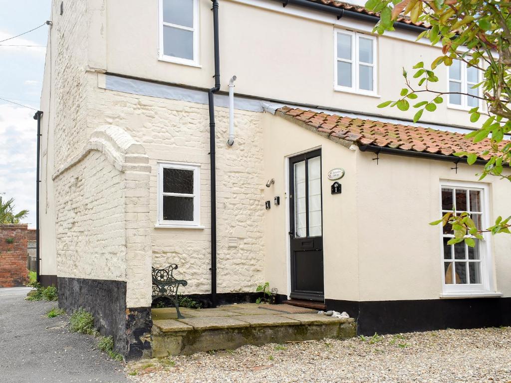 a white brick house with a black door at September Cottage in Wells next the Sea