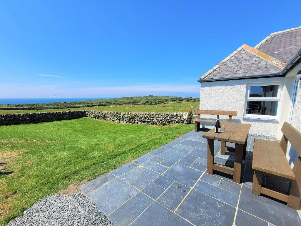 a patio with a bench and a stone wall at Garrarie Cottage in Monreith