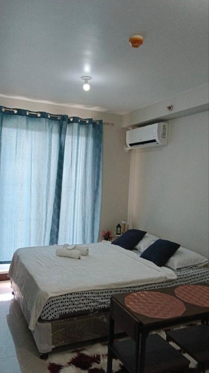 a bedroom with a large bed with blue curtains at Seaview and Cityview Mactan,Cebu in Lapu Lapu City