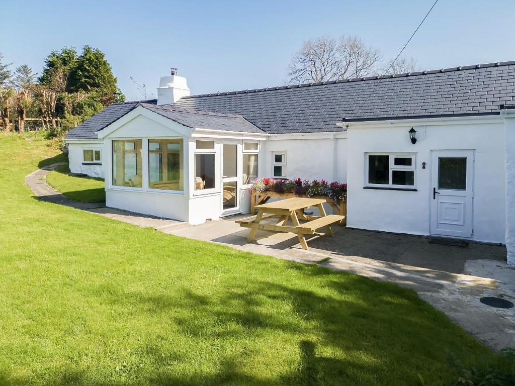 a white cottage with a picnic table in a yard at Bryn Eithin in Moel-tryfan