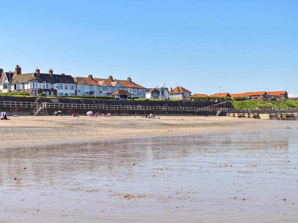 a beach with houses and people sitting on the sand at Wild Waves in Hornsea