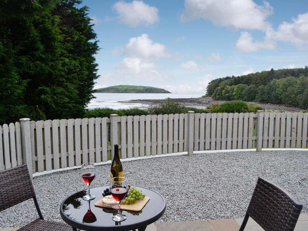 a table with two glasses of wine and a plate of grapes at The Nook At Balcary in Auchencairn