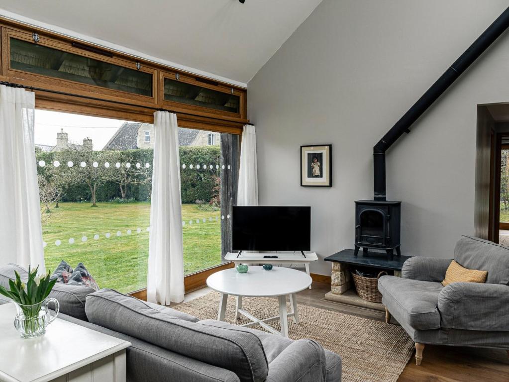 a living room with a large window and a tv at The Barn At Daubeneys in Colerne