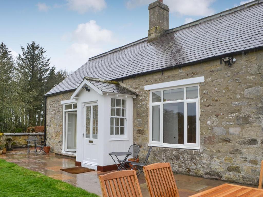 a stone cottage with a white door and windows at Croft Cottage in Sharperton