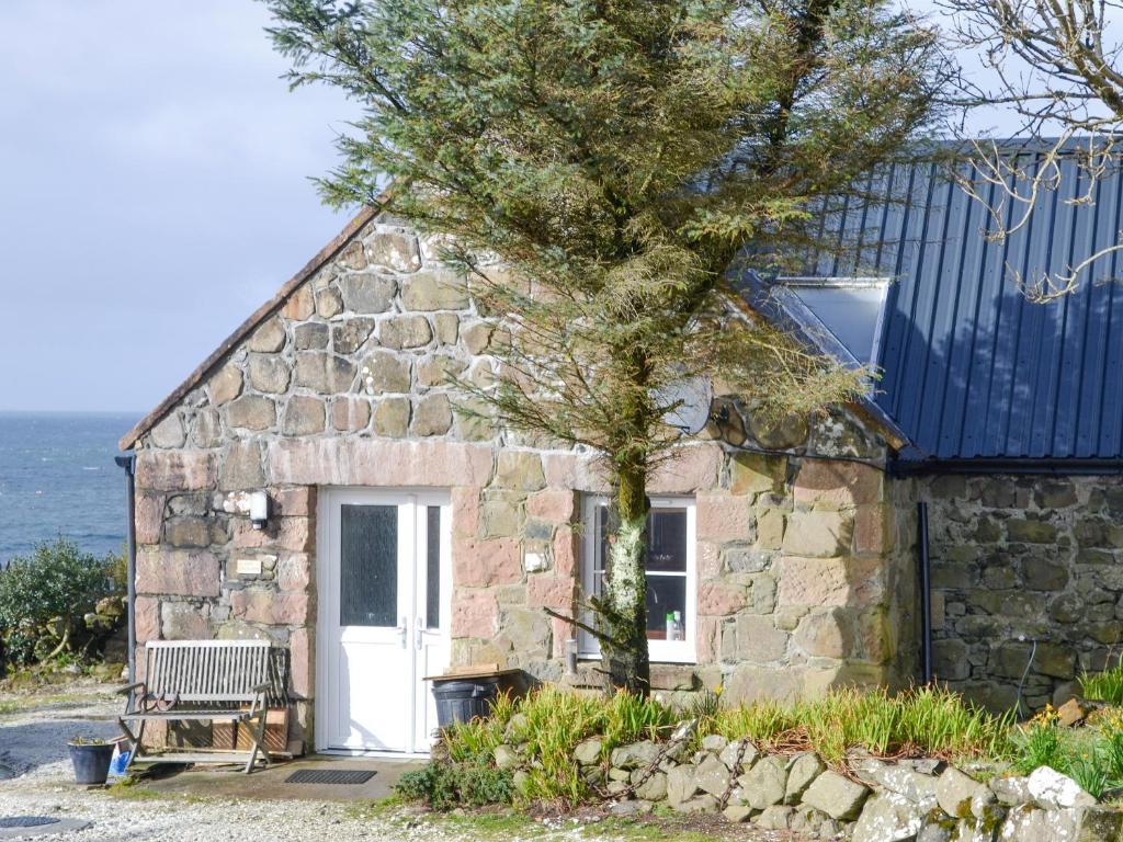 a stone cottage with a tree in front of it at The Old Dye House in Hallin