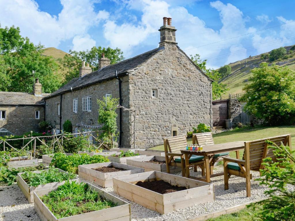 a garden with a table and chairs in front of a building at Wellside Cottage in Starbotton