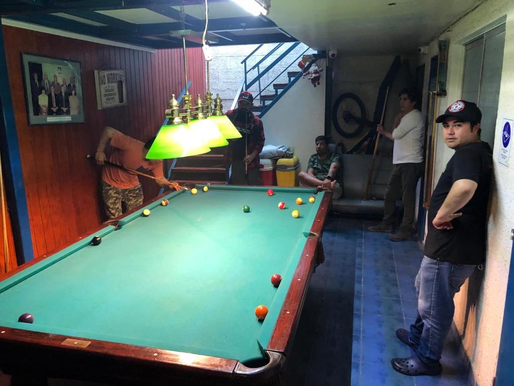 a group of men standing around a pool table at Hernanparapente like your home in Iquique